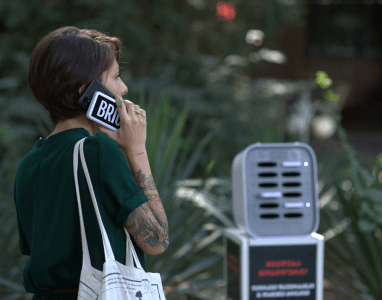 Ragazza che usa il telefono mentre lo carica con un mattone